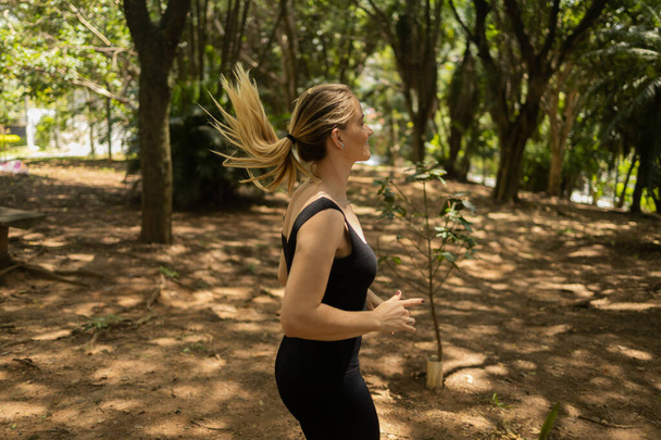Fiatal nő fut és kocog egy parkban a szabadban. Sportoló női személy edzés közben. Jó érzés, egészséges koncepció. Kiváló minőségű fénykép - Fotó, kép
