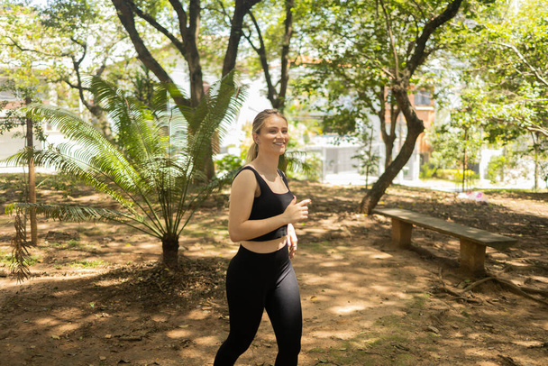 Young woman running and jogging at a park outdoors. Athlete female person during workout. Feel good, healthy concept. High quality photo - Фото, зображення