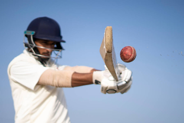 Ein Cricketspieler, der zu Testspielen in weißem Dress auf dem Spielfeld Cricket spielt. Sportlerin schlägt auf Cricketball ein. - Foto, Bild
