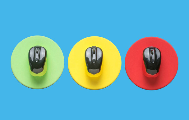 Tres ratones de ordenador multicolores en círculos de tres colores sobre un fondo azul. Concepto mínimo de accesorios inalámbricos para ordenador. - Foto, Imagen
