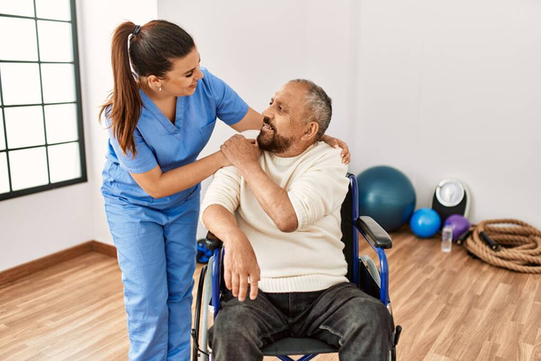 Starszy mężczyzna siedzący na wózku inwalidzkim i geriatryczna pielęgniarka w klinice rehabilitacyjnej - Zdjęcie, obraz