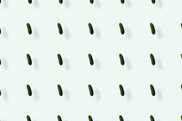 Πολύχρωμο μοτίβο από φρέσκα αγγούρια σε λευκό φόντο με σκιές. Στο πάνω μέρος. Επίπεδη. Σχεδιασμός ποπ τέχνης - Φωτογραφία, εικόνα