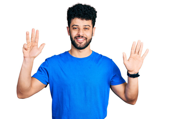 Young arab man with beard wearing casual blue t shirt showing and pointing up with fingers number nine while smiling confident and happy.  - Photo, Image