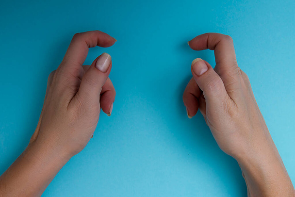 Female hands holding an object on a blue background - Foto, afbeelding
