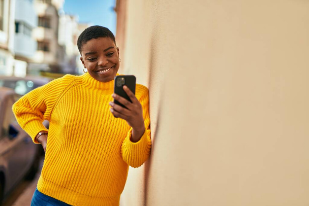 Young african american woman smiling happy using smartphone at the city - Foto, imagen