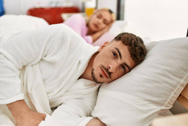 Young caucasian couple lying on the bed. Man looking to the camera at home. - Foto, imagen