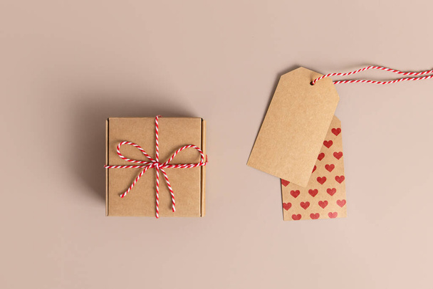 Vintage paper label with a red heart. Hand drawn retro tag or banner with a rope. Isolated on beige background. Perfect romantic decoration for birthday, Christmas or St. Valentines day. - Photo, image