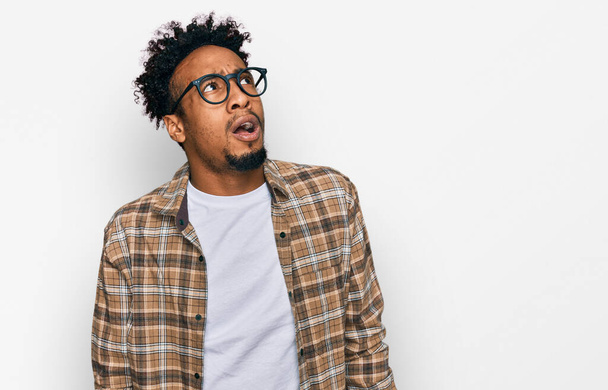 Young african american man with beard wearing casual clothes and glasses angry and mad screaming frustrated and furious, shouting with anger. rage and aggressive concept.  - Foto, Imagen