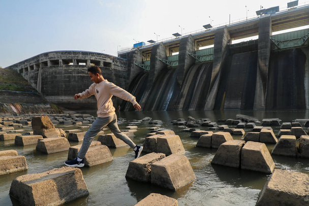 Nuori mies hyppää betonilohkojen alle Bendungan Sampean Bar Dam - Valokuva, kuva