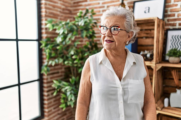 Oudere grijsharige vrouw lacht zelfverzekerd thuis - Foto, afbeelding