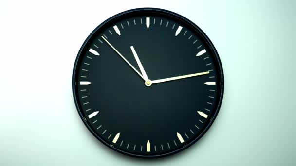 Reloj de pared negro está mostrando el tiempo. Rotación lenta en sentido horario sobre fondo blanco. - Metraje, vídeo