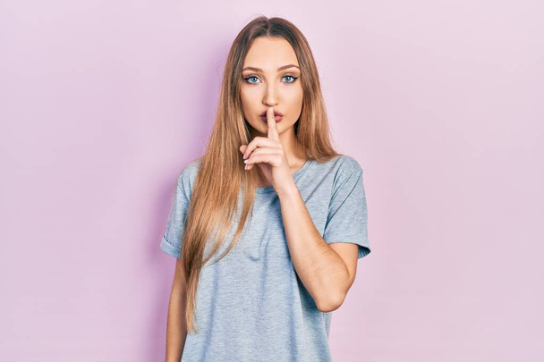 Young blonde girl wearing casual t shirt asking to be quiet with finger on lips. silence and secret concept.  - Fotografie, Obrázek