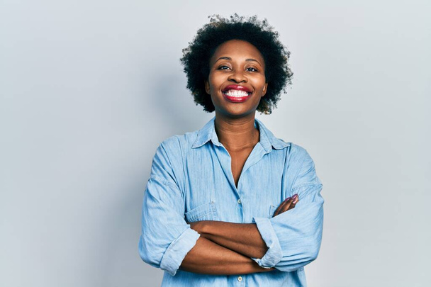 Mujer afroamericana joven vistiendo ropa casual cara feliz sonriendo con los brazos cruzados mirando a la cámara. persona positiva.  - Foto, Imagen
