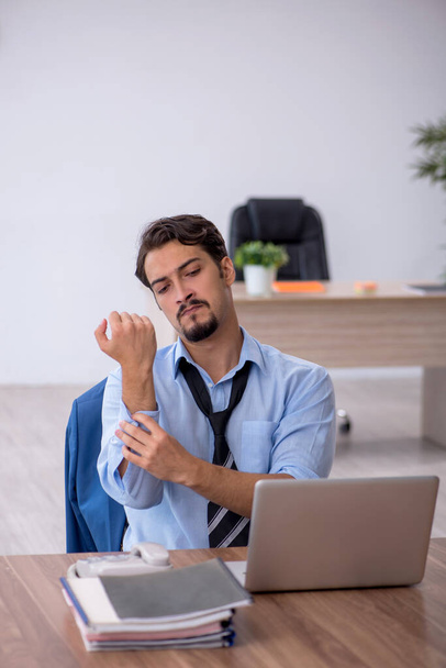 Joven empleado masculino descontento con el trabajo excesivo en la oficina - Foto, Imagen