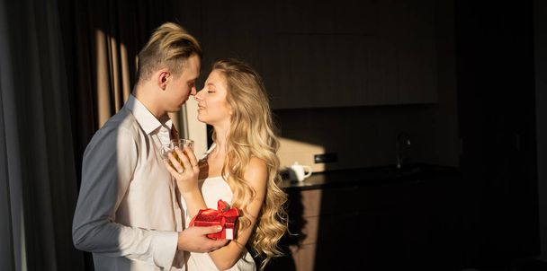 Portrait of a young caucasian couple in casual clothes. The husband surprised his wife with a gift box and the wife was excited and kissed her husband after opening the gift on the anniversary day or valentine's day. copy space - Фото, изображение
