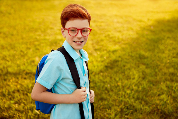 Redhead pupil with backpack in park - Photo, image