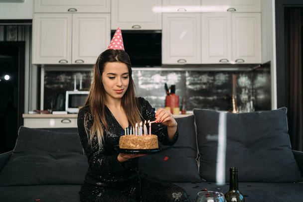 Usmívající se mladá žena zapalující svíčky na dortu, narozeninová oslava doma, sladký dezert se svíčkami, oslava 25. narozenin evropské dívky, koncept oslav oslav na dálku - Fotografie, Obrázek
