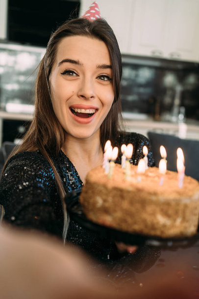 Idea compleanno. Felice donna caucasica blogger che tiene la torta con la candela sorridente alla fotocamera mentre festeggia il compleanno a casa, primo piano. focus selettivo - Foto, immagini