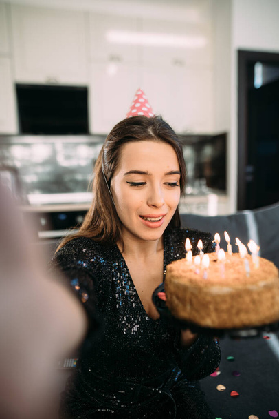 Smiling positive young woman celebrating birthday at home, holding cake with candles, girl 25 years old celebrates one holiday, happy birthday concept - Фото, изображение