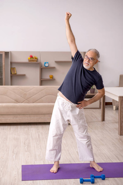 Oude man die thuis sport oefeningen doet - Foto, afbeelding