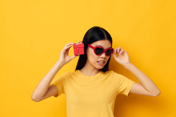 woman with Asian appearance with gift boxes in hands fun posing yellow background unaltered - Фото, изображение