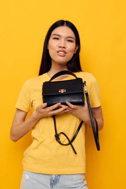 Portrait Asian beautiful young woman female clutch accessories posing yellow background unaltered - Fotografie, Obrázek