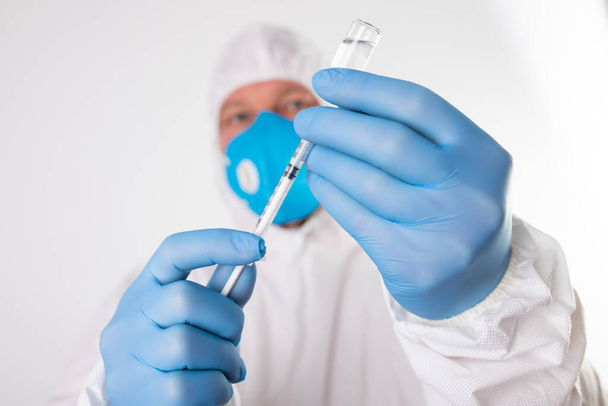 COVID-19 coronavirus vaccine. Vaccination concept. Doctor's hand in blue gloves hold medicine vaccine vial bottle and syringe.  - Photo, image