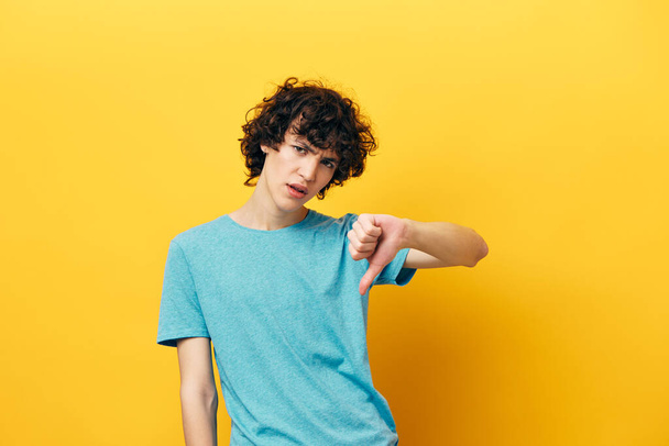 curly guy showing thumb down on yellow background lifestyle - Fotó, kép