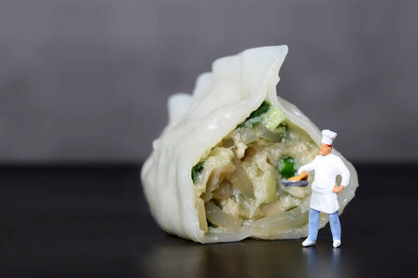 Gestoomde knoedels en een miniatuur chef-kok. Miniatuur mensen en dumplings met zakelijke concepten. - Foto, afbeelding