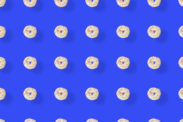 Patrón colorido de rosquillas acristaladas blancas aisladas sobre fondo azul con sombras. Rosquillas. Vista superior. Puesta plana - Foto, Imagen
