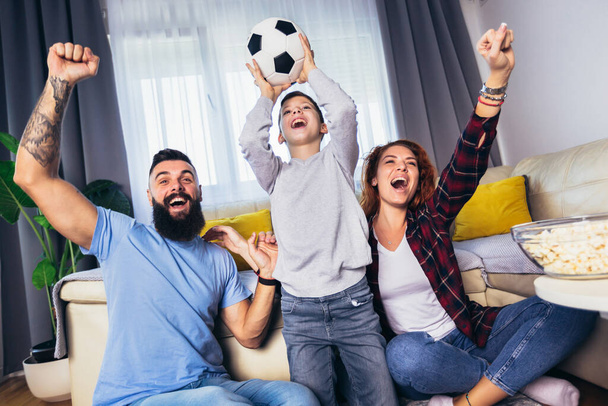 Famiglia di fan che guardano una partita di calcio in TV a casa - Foto, immagini