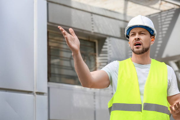 Male builder with ear plugs working outdoors - Photo, Image