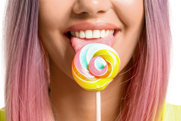 Giovane donna mangiare lecca-lecca su sfondo bianco - Foto, immagini