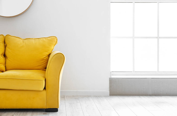 Зручний жовтий диван біля світлої стіни
 - Фото, зображення