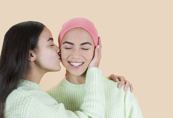 癌の美しい女性姉妹はピンクのスカーフでキスをし - 写真・画像