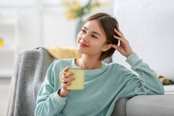Beautiful young woman drinking tasty tea on at home - Zdjęcie, obraz