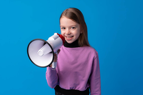 Child girl using megaphone against blue background - Fotó, kép
