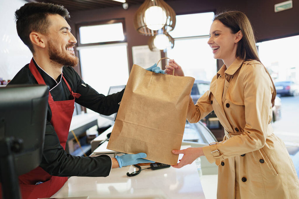 Помічник магазину обробляє сумку для покупки жінки-клієнта в продуктовому магазині
 - Фото, зображення