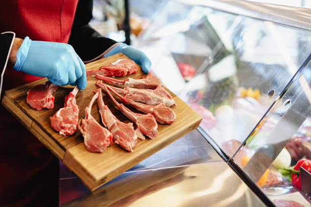 Close up of a butcher setting raw lamb ribs in a butcher shop - Фото, зображення
