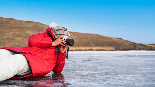 バイカル湖の氷の上にカメラを持つ観光客の写真家 - 写真・画像