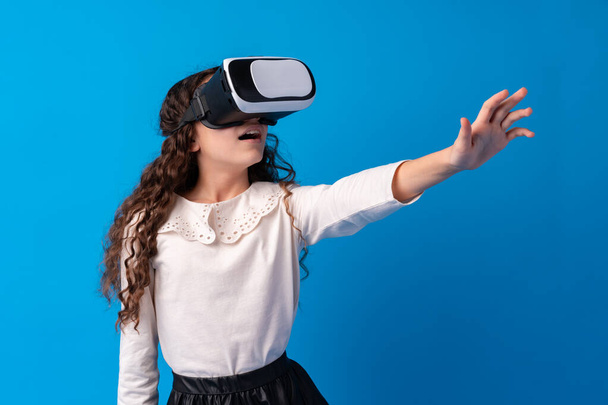Girl with virtual reality glasses on blue background. - Foto, imagen