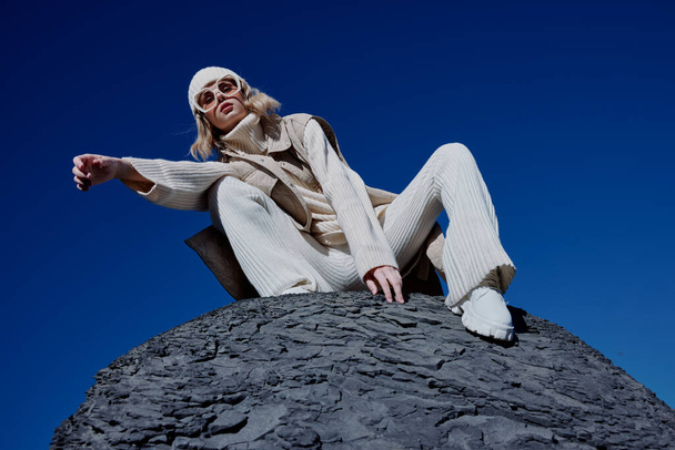 γυναίκα κάθεται σε ένα πέτρινο γαλάζιο ουρανό σε έναν τρόπο ζωής καπέλο - Φωτογραφία, εικόνα
