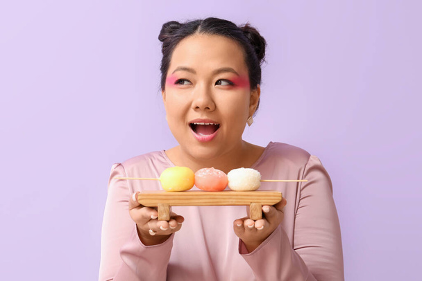 Beautiful Asian woman with tasty Japanese mochi on color background - Foto, Imagen