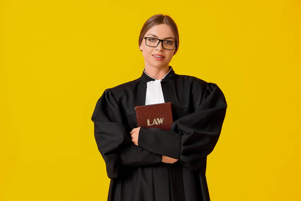 Young female judge with book on color background - Photo, Image