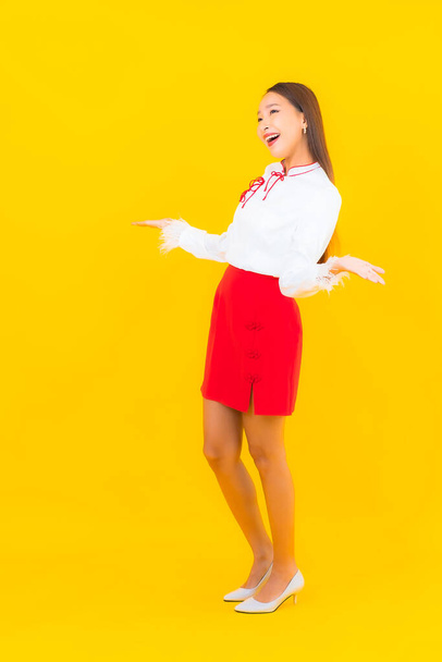 Портрет красивая молодая азиатка улыбается в действии на желтом фоне - Фото, изображение