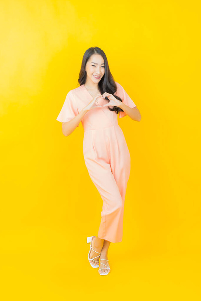 Portrait belle jeune femme asiatique sourire avec action sur fond de couleur - Photo, image