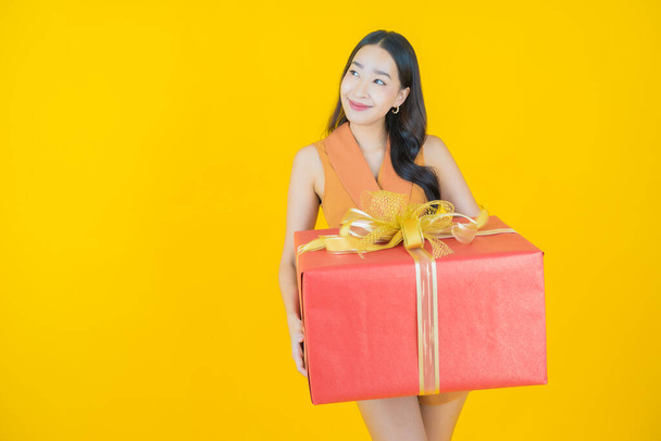 Portrait beautiful young asian woman smile with red gift box on color background - Zdjęcie, obraz