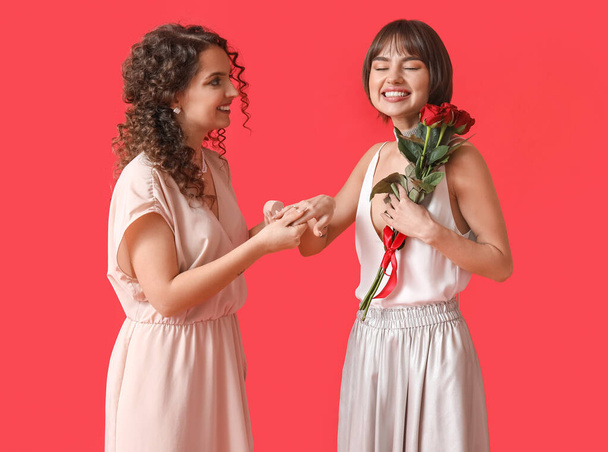 Young lesbian woman proposing to her girlfriend on color background - Photo, Image