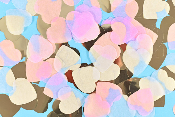 Heart shaped pink, white and golden paper confetti on blue background - Zdjęcie, obraz