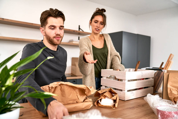 Caucasian couple arguing while packing together some kitchen stuff - Fotó, kép
